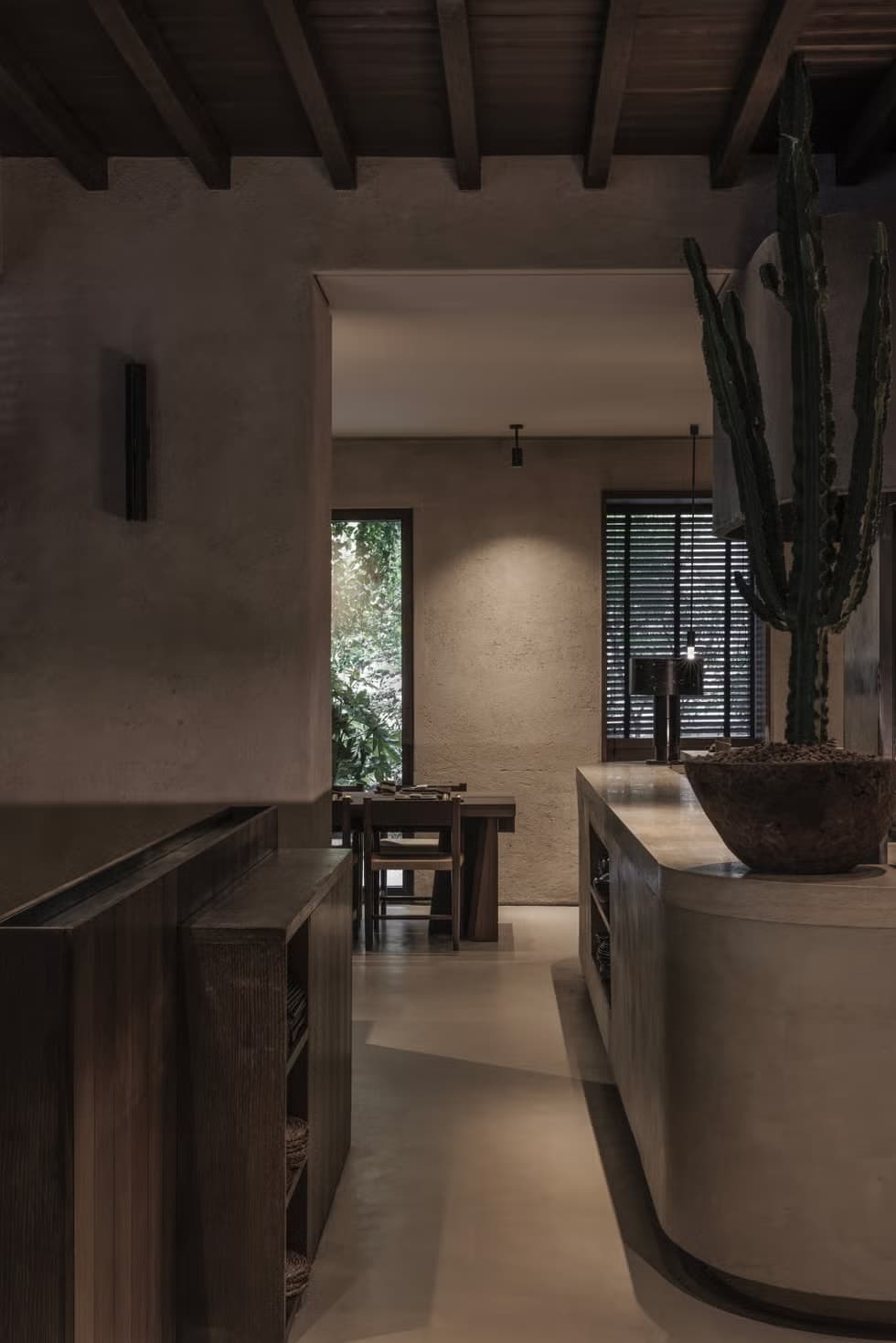 Vista interna del ristorante con bancone di servizio, elemento curvo in cemento e cactus decorativo
