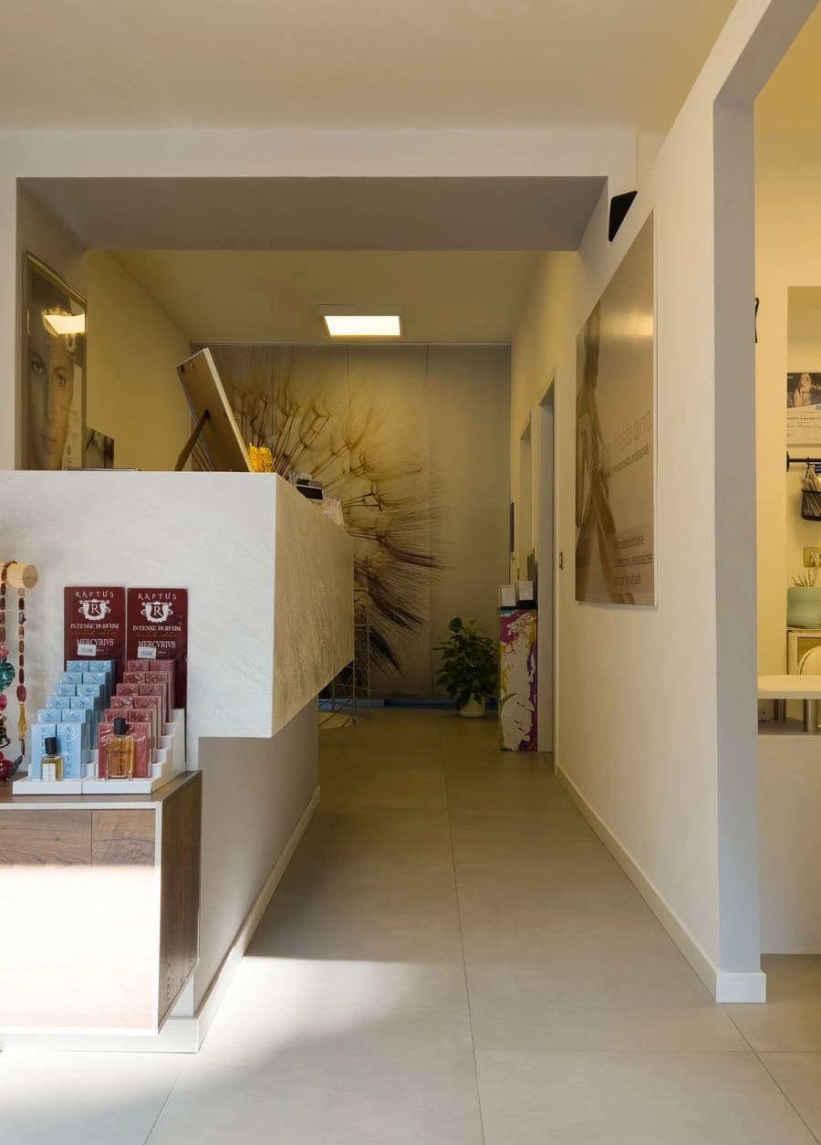 Entrée avec comptoir réception, produits cosmétiques et couloir vers les cabines