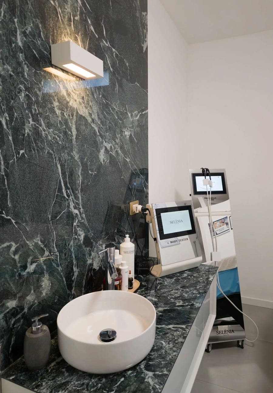 Détail cabine avec vasque, équipements esthétiques et revêtement effet marbre foncé