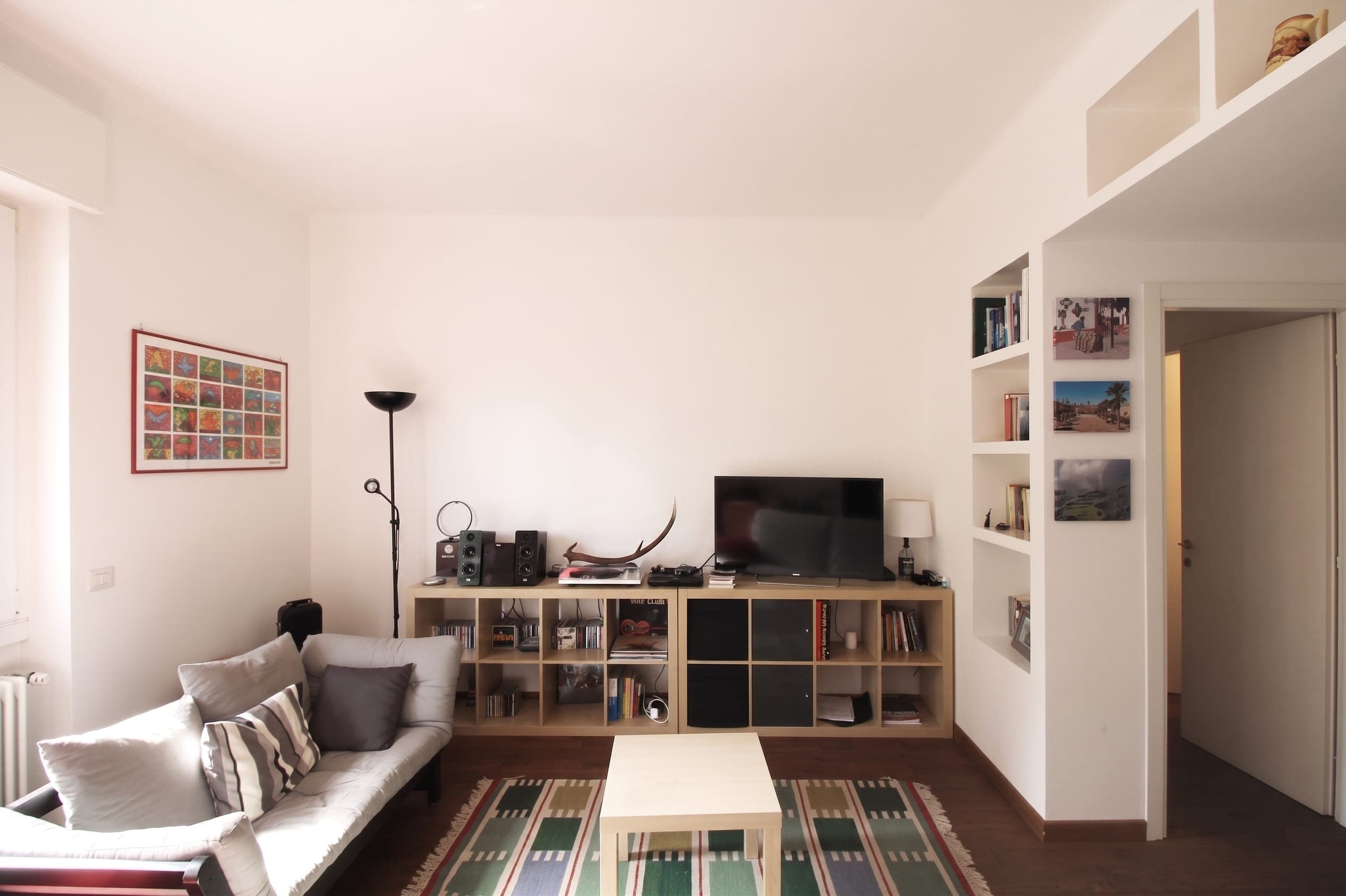 Soggiorno con divano, mobile TV, libreria a nicchia e tappeto geometrico verde