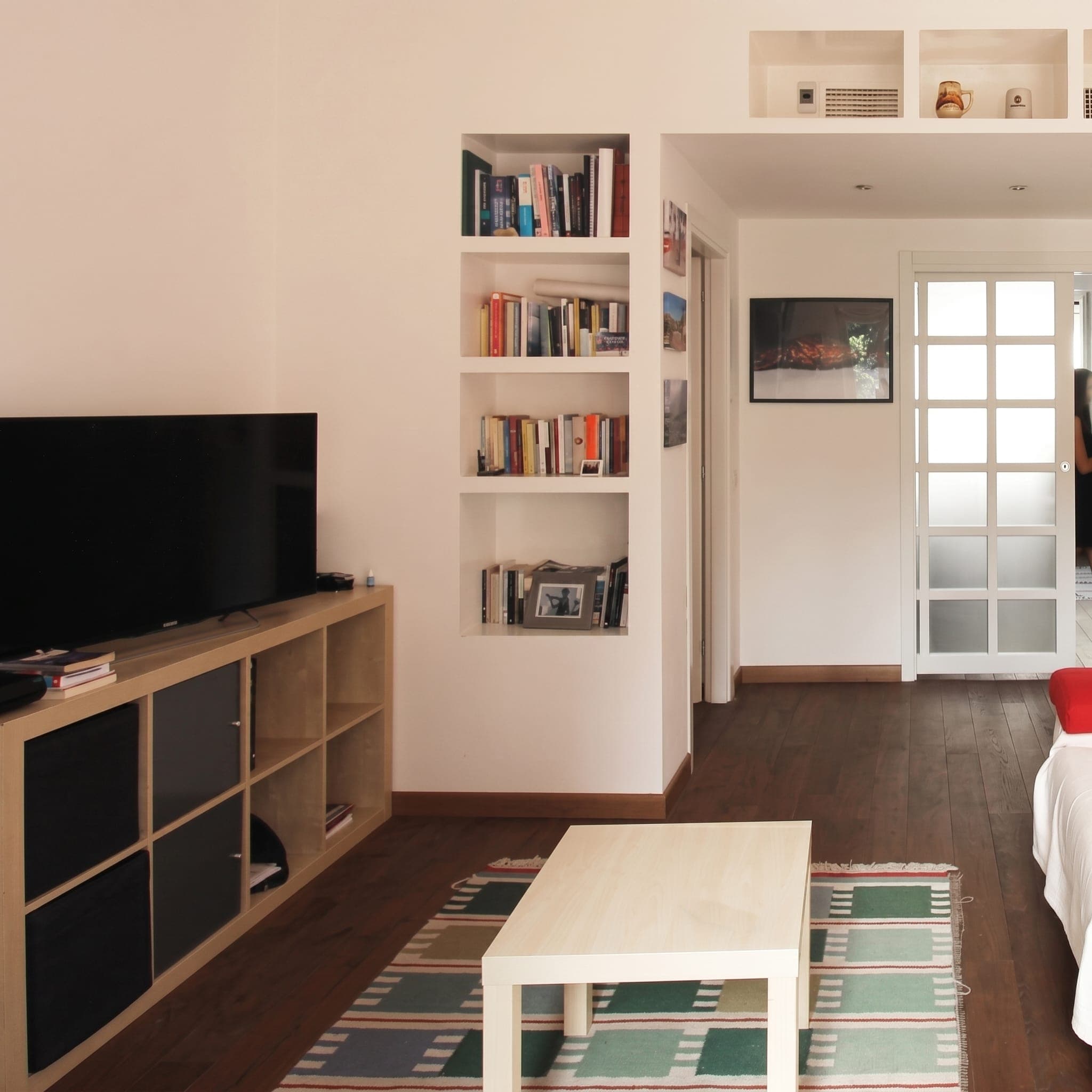 Soggiorno con mobile TV, libreria a nicchia, porta vetrata e tappeto geometrico