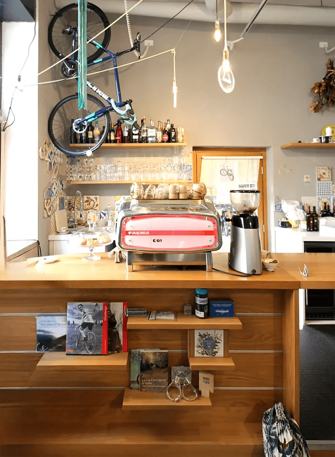 Wooden bar counter with Faema E61 machine, hanging bicycle and decorative bulbs