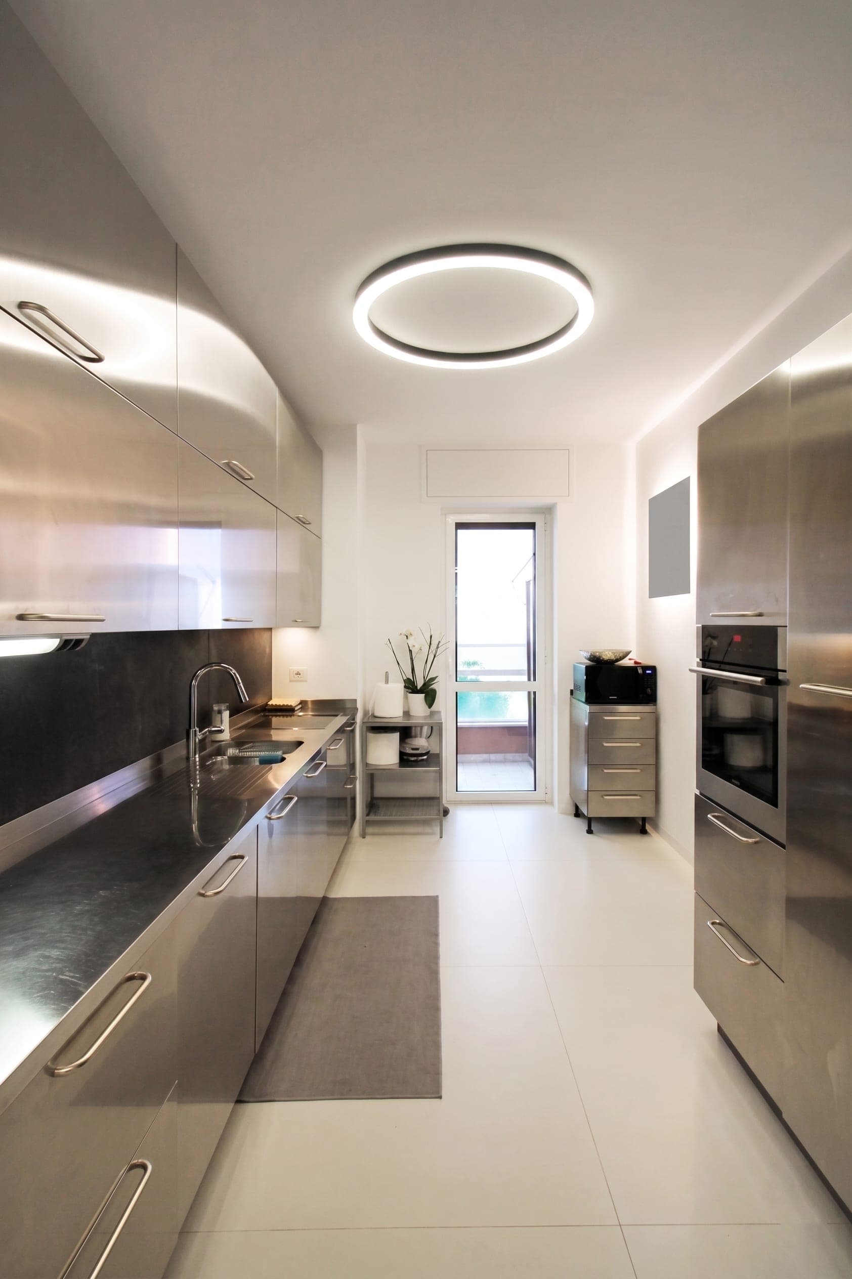 Cucina moderna con piano scuro, elettrodomestici integrati e plafoniera circolare