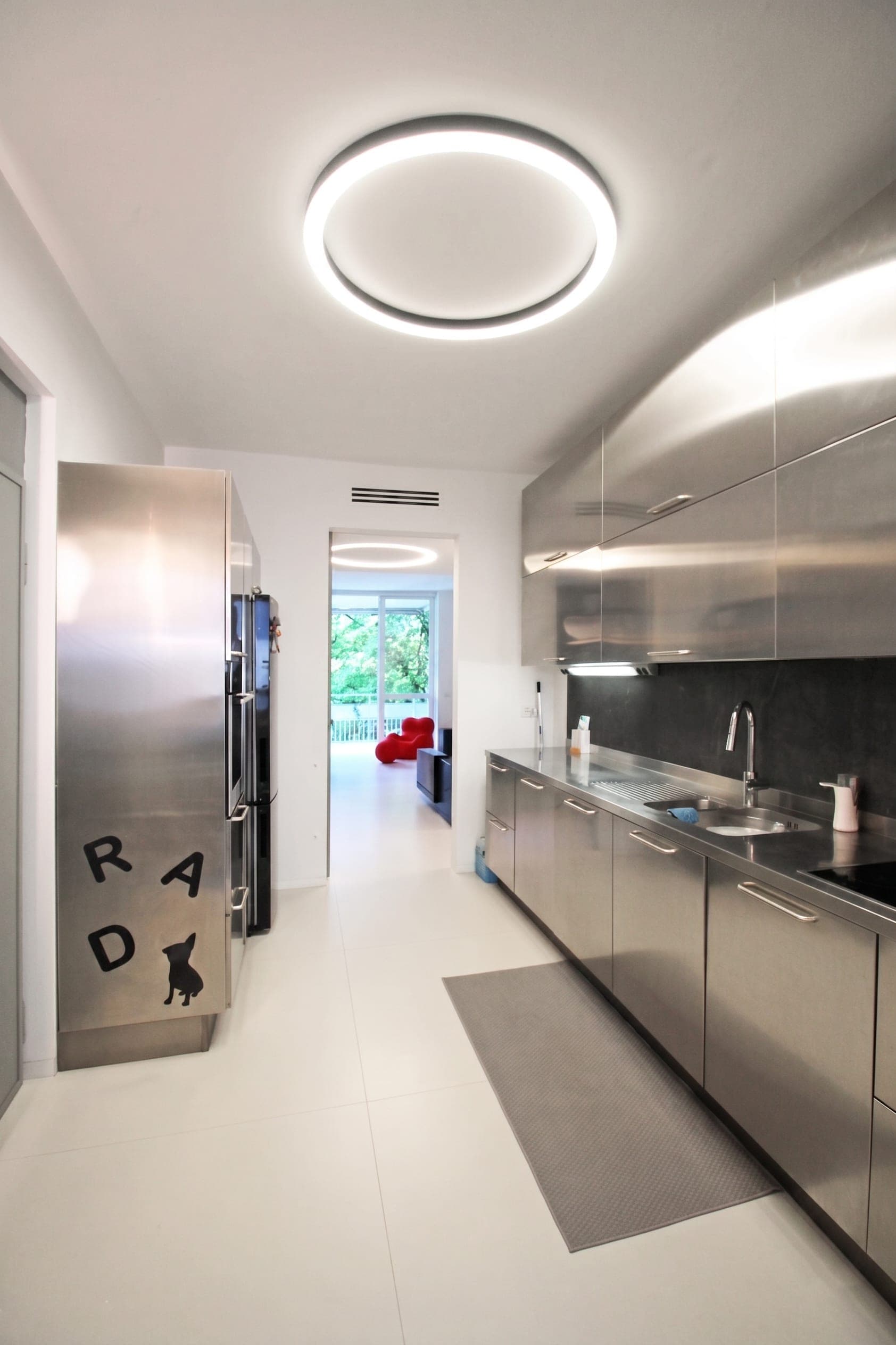 Cucina con finiture in acciaio, frigorifero e schienale scuro