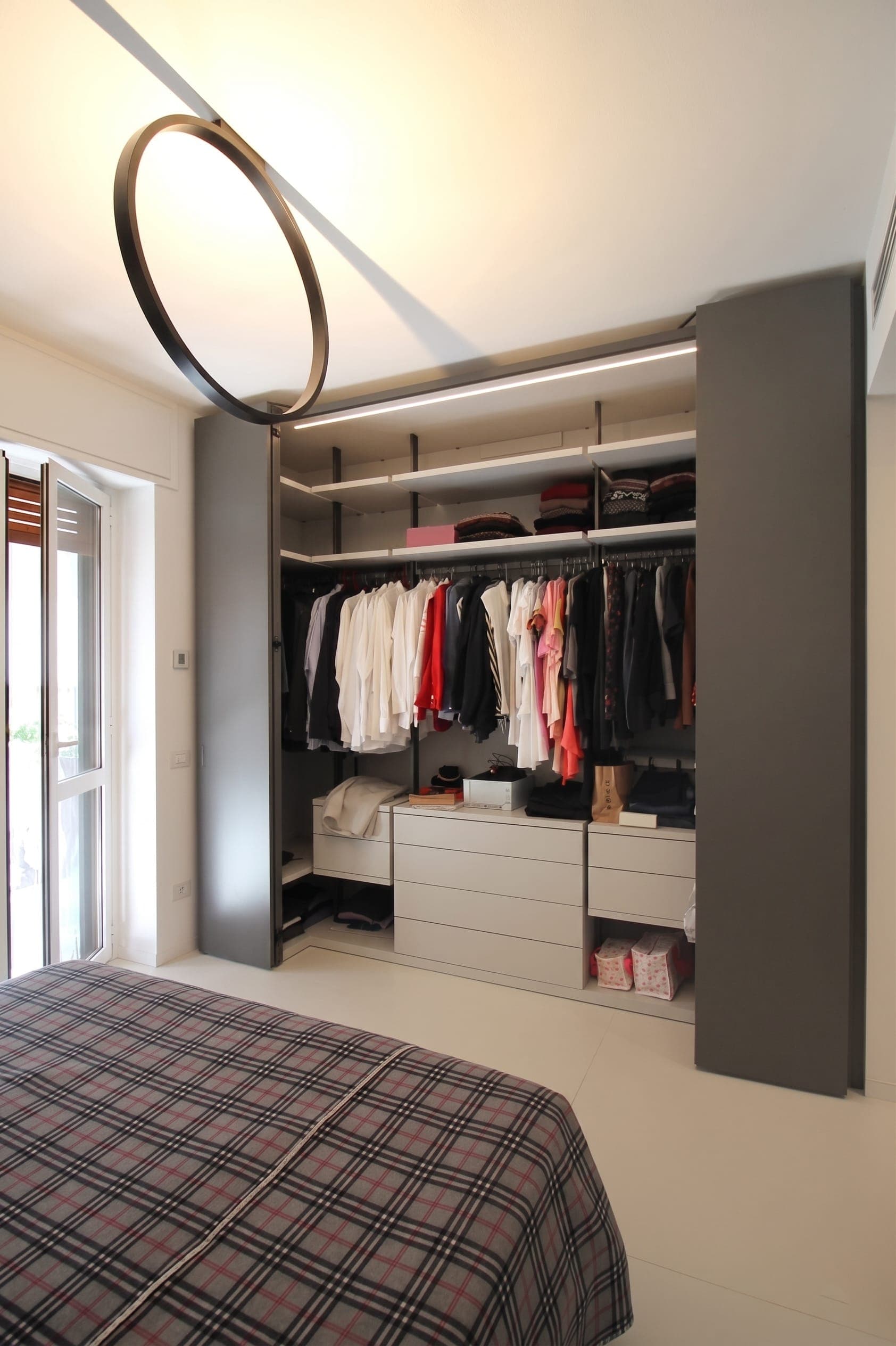 Cabina armadio aperta con abiti, cassettiera e illuminazione interna