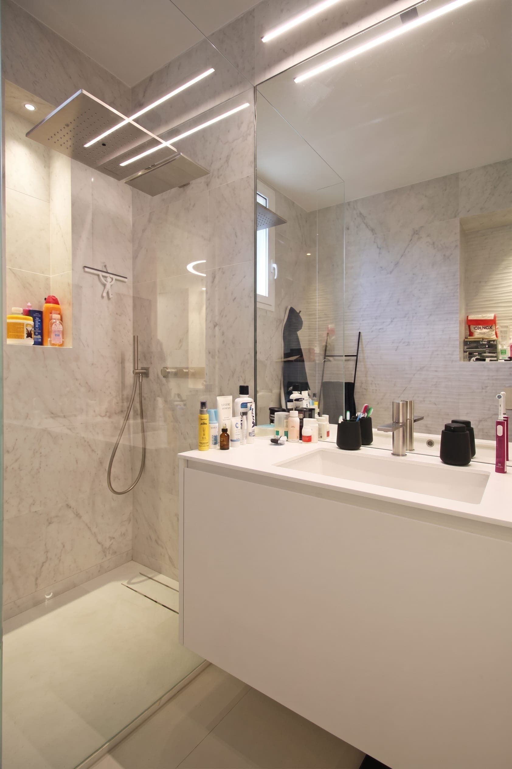 Bagno padronale con grande specchio, doccia in vetro e rivestimenti chiari