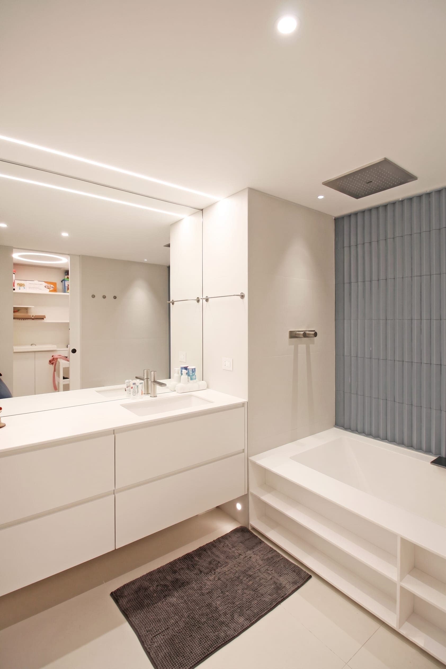 Camera con armadi bianchi, pannello verticale grigio e dettaglio soffitto scuro