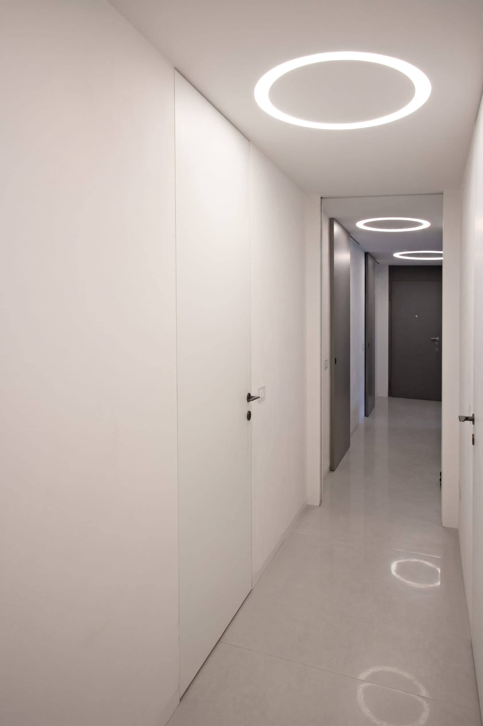 Bagno bianco minimalista con sanitari, specchio e doccia a vetro
