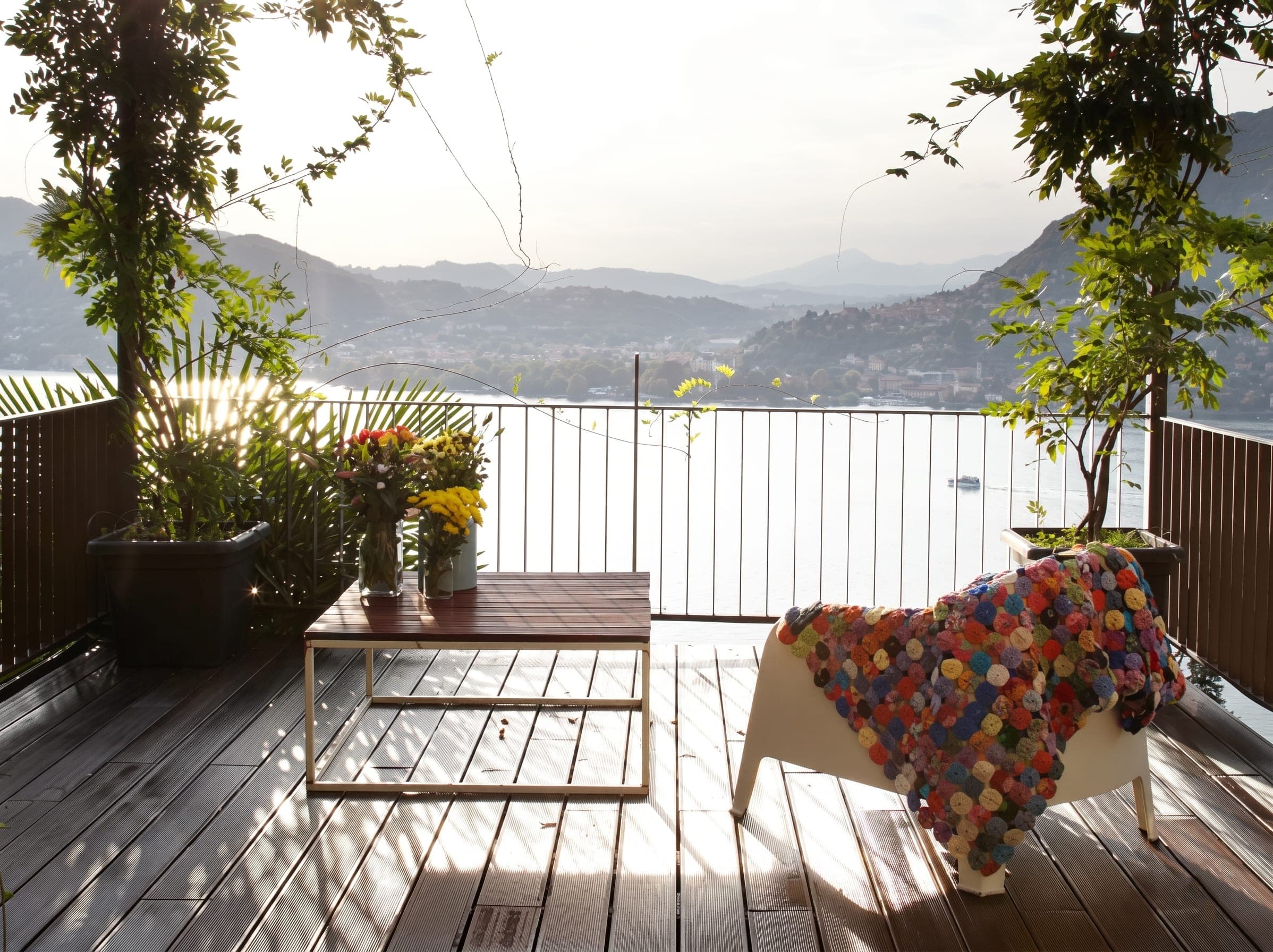 Terrazza panoramica con pavimento in legno, poltrona colorata e vista sulle colline