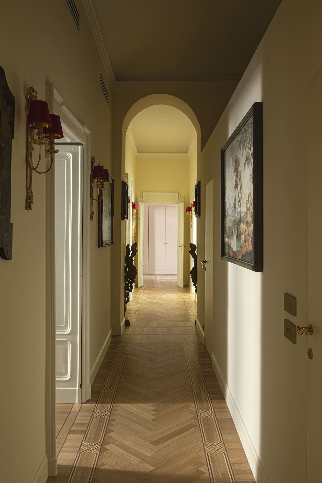 Historic hallway with inlaid parquet, golden sconces, antique paintings and arched vault