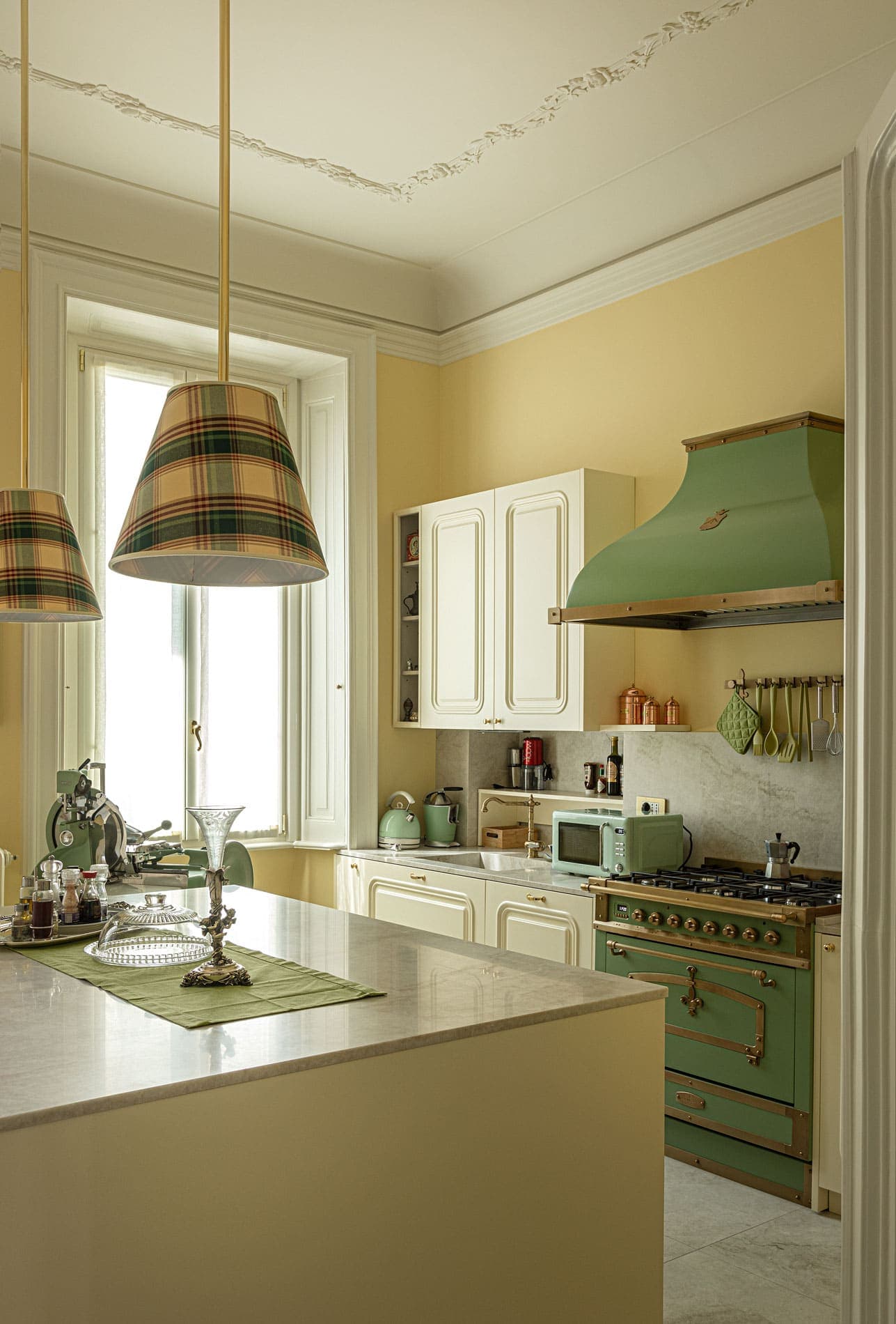Classic kitchen with green Lacanche stove, tartan lampshades and marble countertop