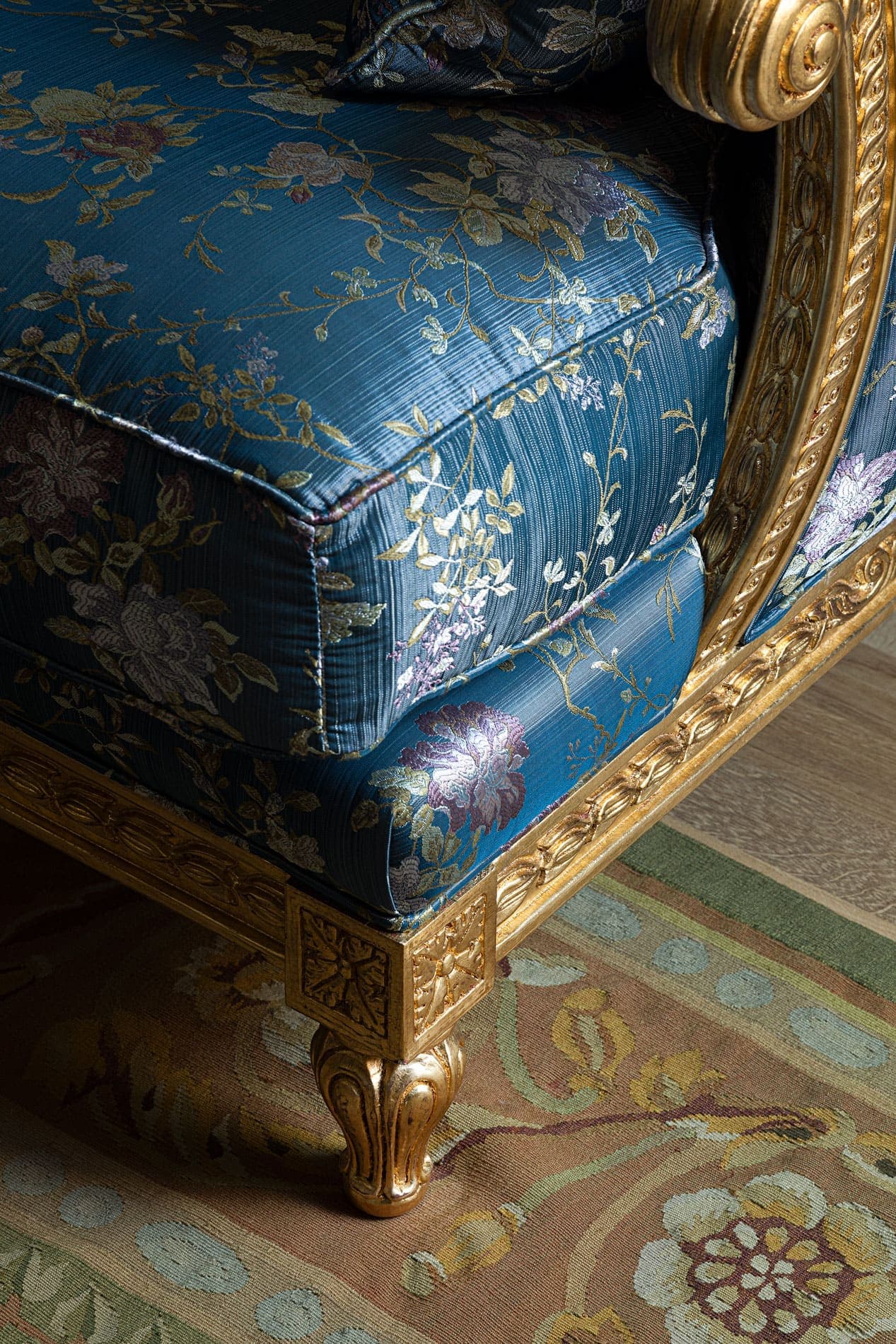 Detail of period sofa with blue floral brocade fabric and golden legs