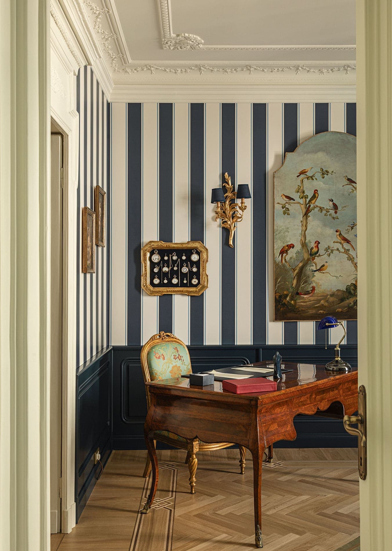 Study with antique desk, blue striped wallpaper, bird painting and golden chair