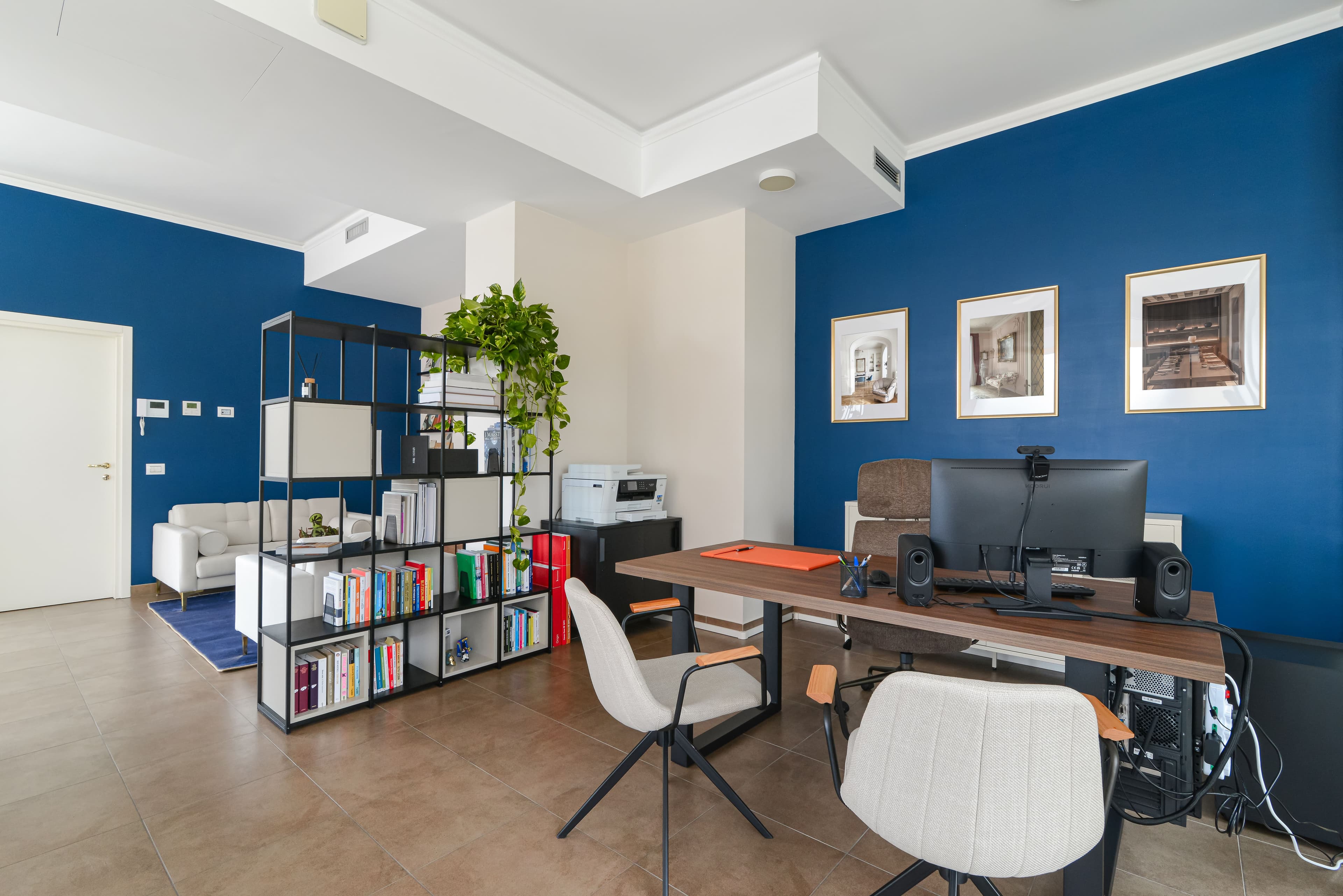 Vista ampia dell ufficio con libreria divisoria e area lounge sullo sfondo