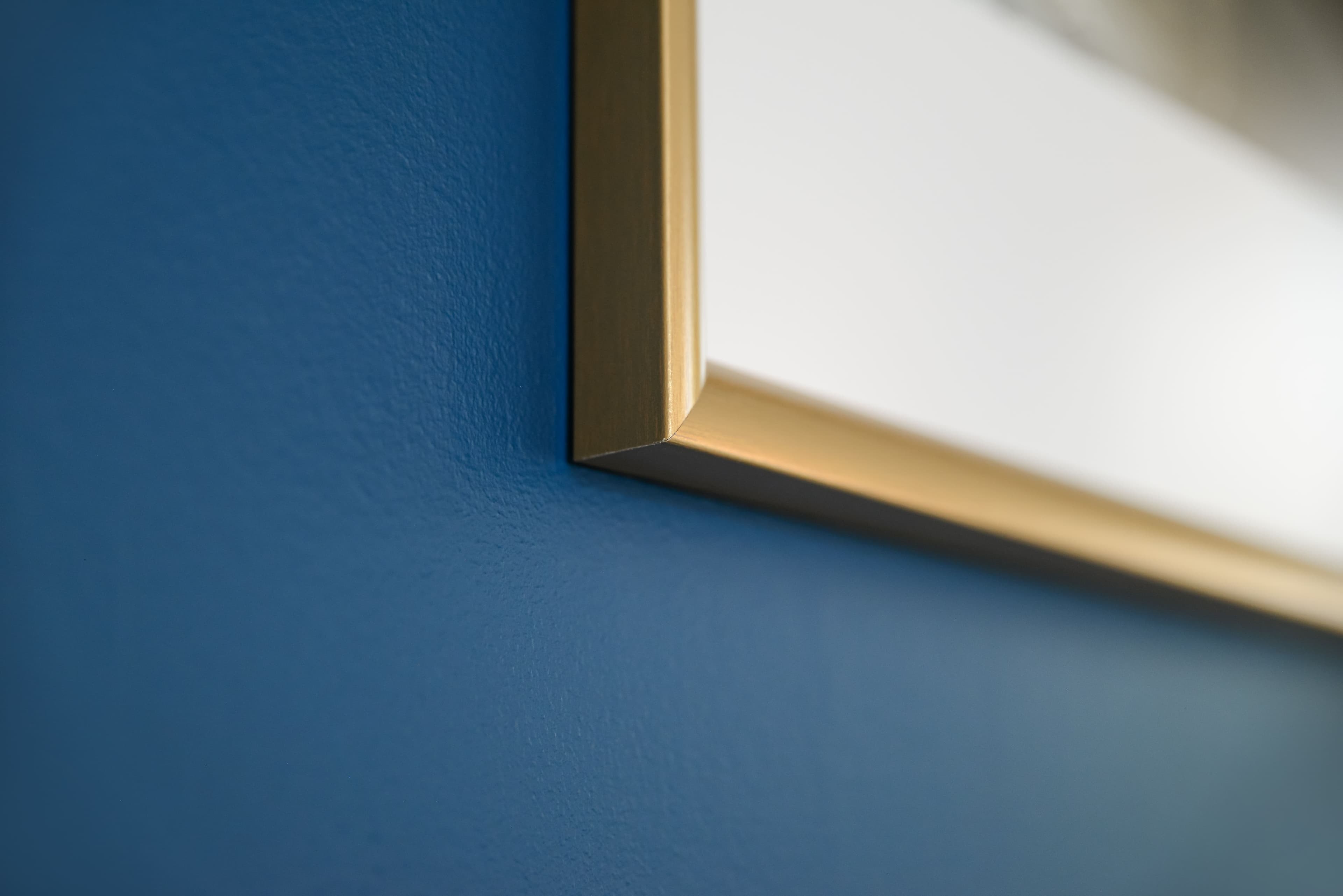 Dettaglio cornice dorata su parete blu