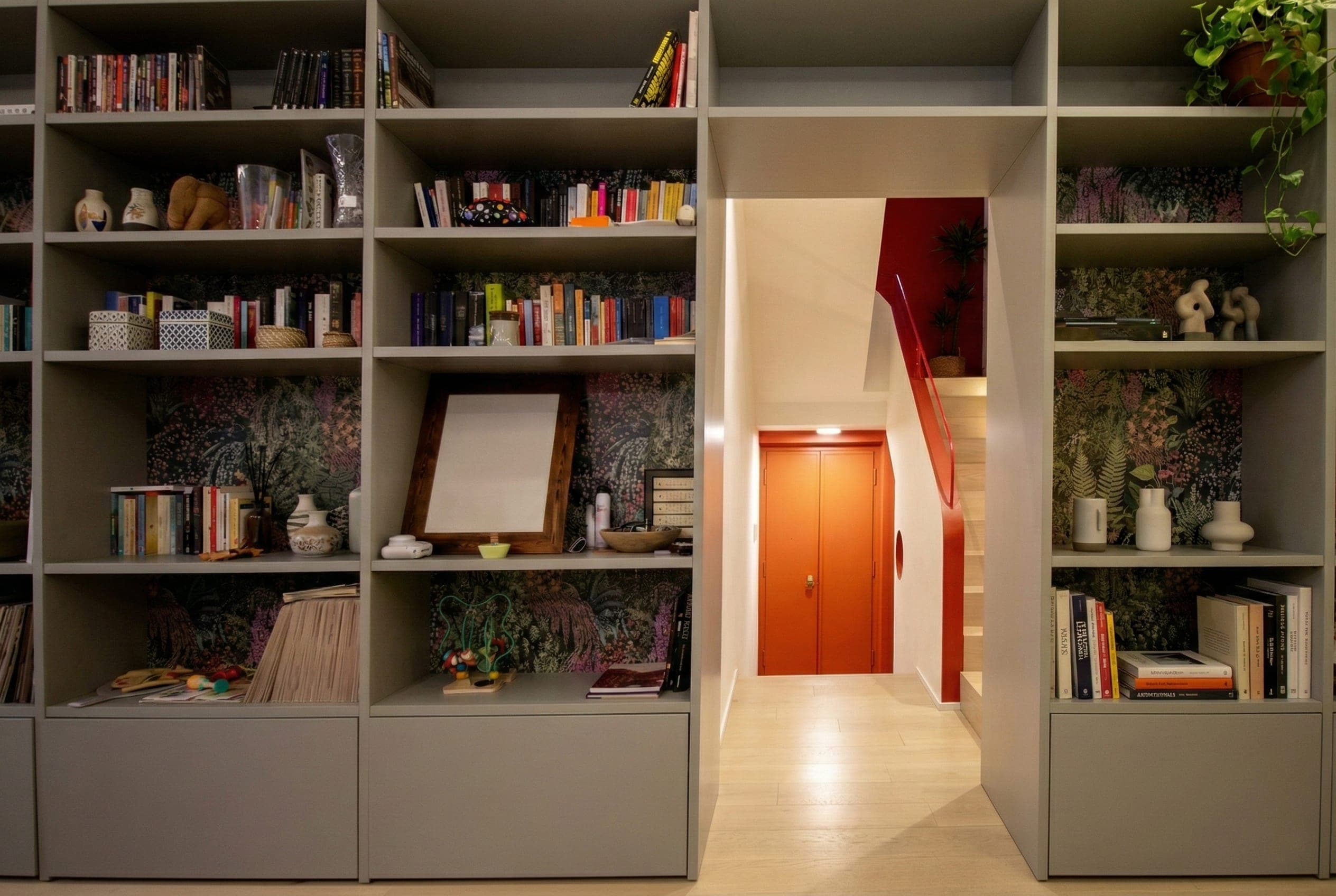 Libreria a parete su misura con carta da parati floreale e porta colorata
