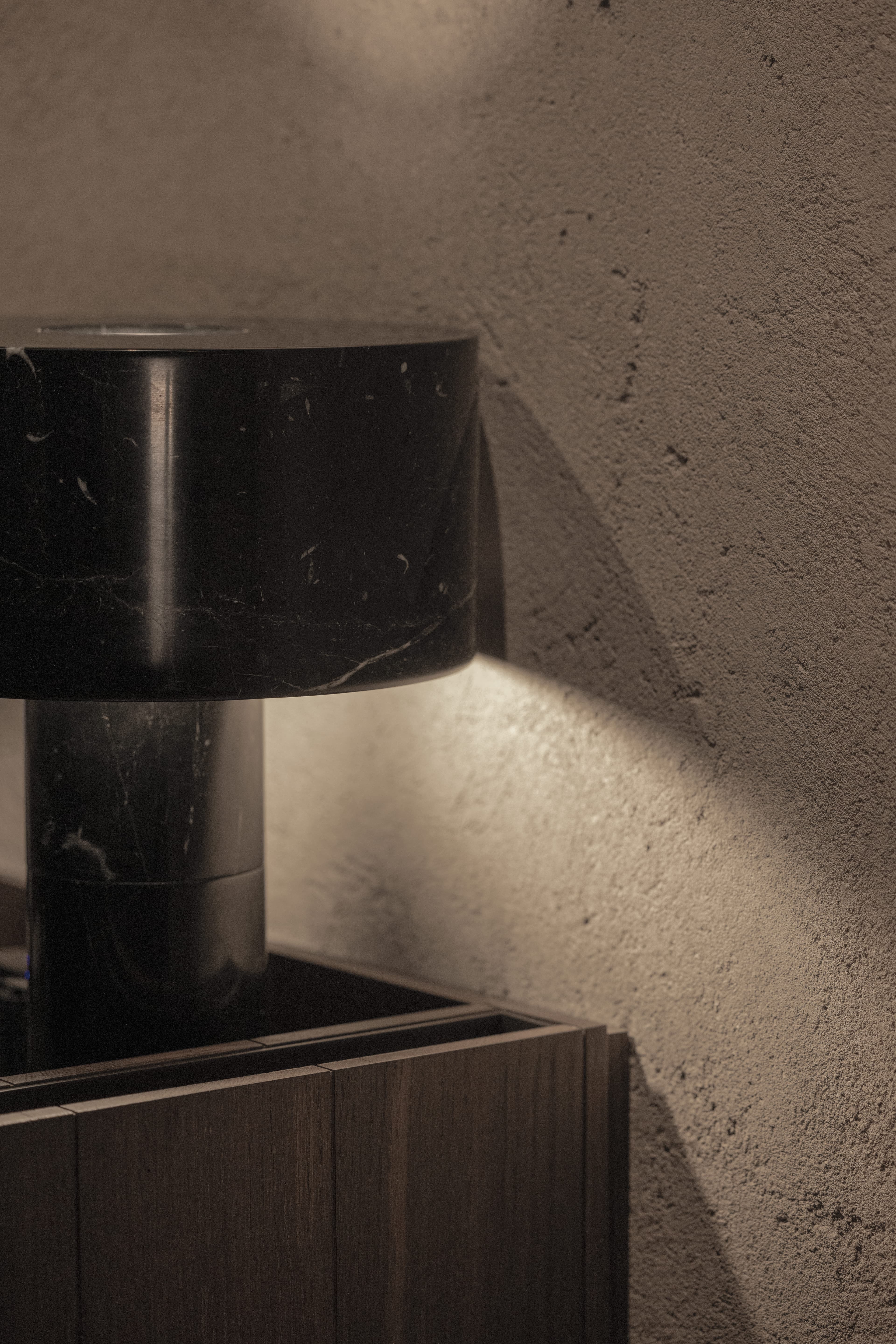 Lampada in pietra di Gilles Caffier con luce riflessa sulla finitura muraria Clayworks demi-rustic