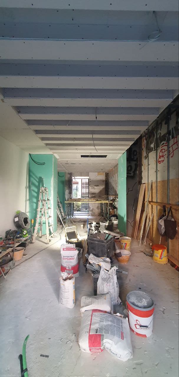 Cantiere in fase intermedia con materiali da costruzione, sacchi di intonaco e pannelli di cartongesso