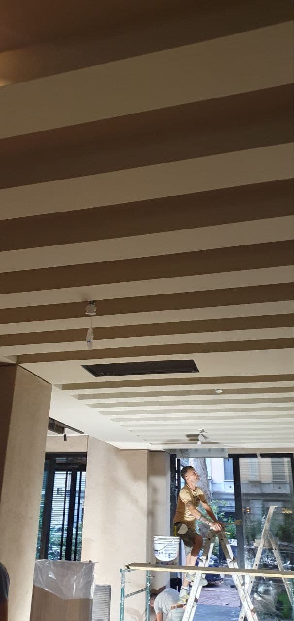 Operaio su ponteggio applica la finitura finale in intonaco al soffitto a travi del ristorante
